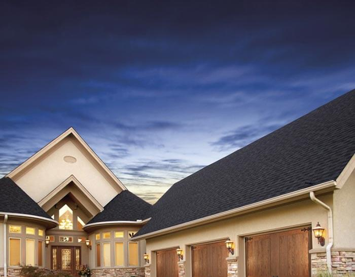 Contemporary home with steep roof and wood garage doors.