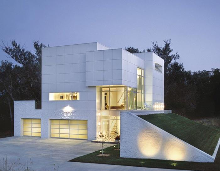 Minimalist white cube-style modern home with glowing lights.