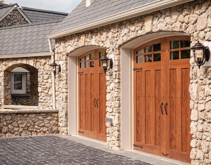 Stone house with wooden double garage doors.
